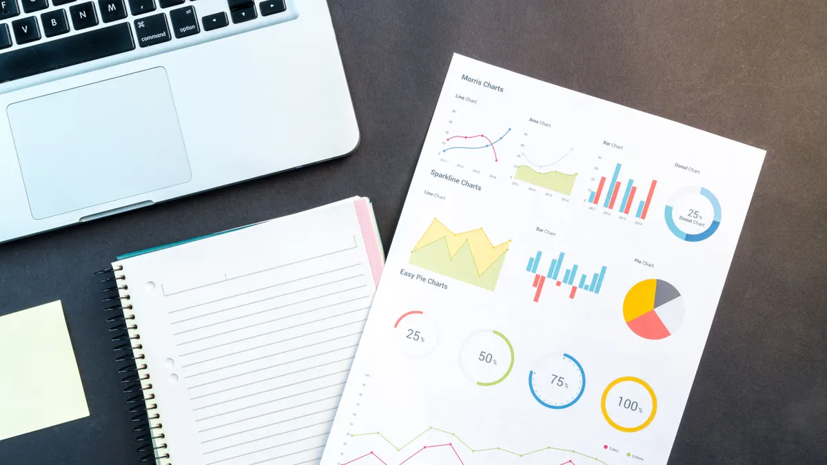 Bing SEO reporting: which metrics to watch every month desk with laptop, notebook, and printed charts